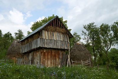 Old wooden house on field against sky