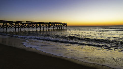 Pier over sea against clear sky during sunset