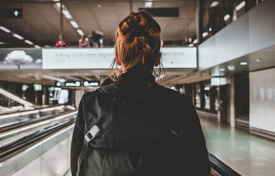 Rear view of woman standing at railroad station