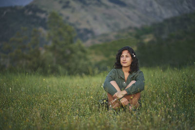 Portrait of a young woman sitting in a meadow at sunset. the sun illuminates her face.