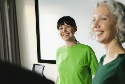 Two happy colleagues in green clothing in office