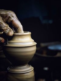 Close-up of hand shaping pottery clay on wheel