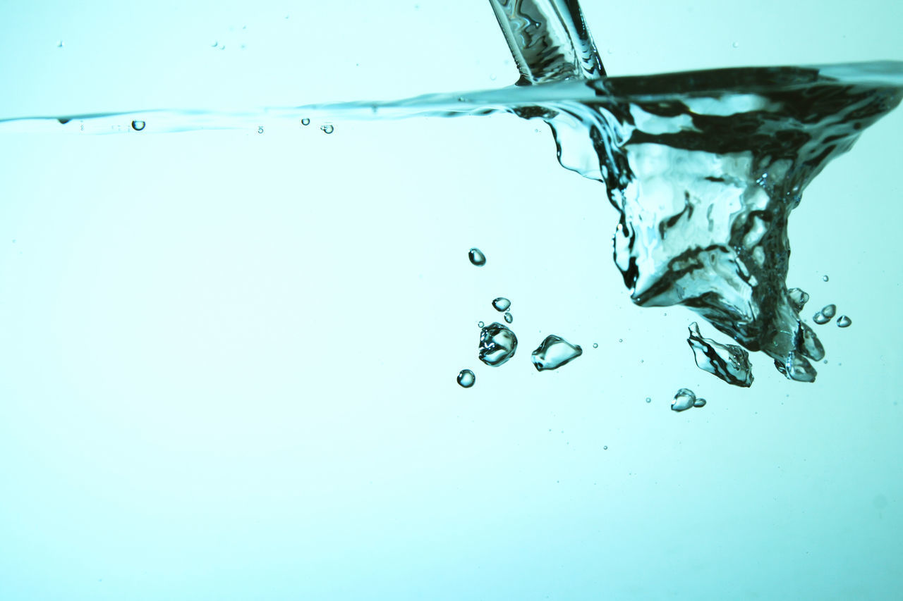 CLOSE-UP OF DROP FALLING ON WATER AGAINST BLUE SKY