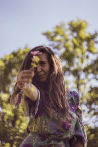 Woman standing by tree against plants