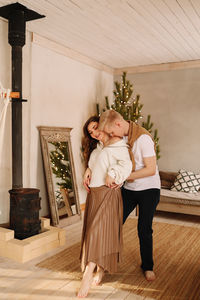 A man and a woman in love embrace give gift gifts celebrate a holiday at the christmas tree at home