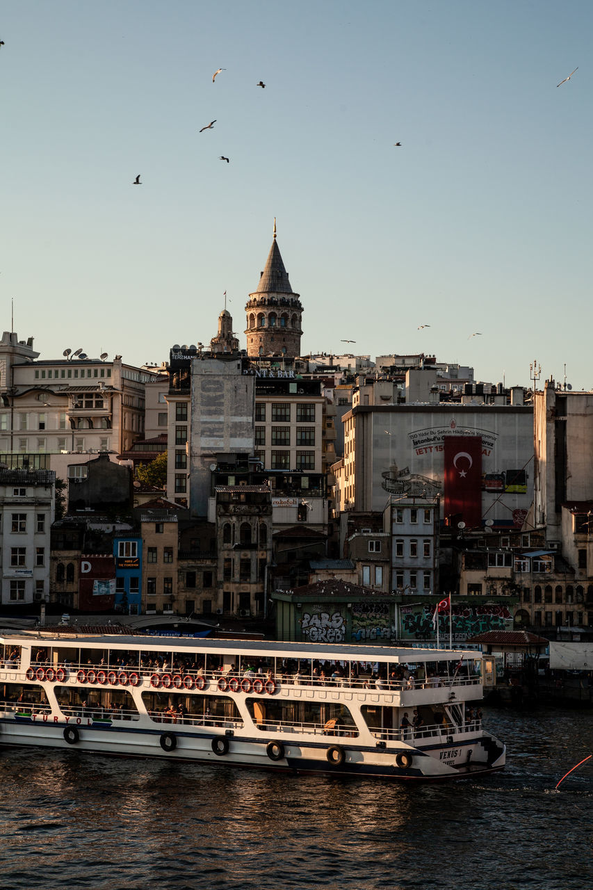 architecture, building exterior, built structure, cityscape, city, water, sky, travel destinations, building, transportation, nautical vessel, nature, sea, evening, urban area, mode of transportation, skyline, bird, travel, clear sky, harbor, ship, animal themes, animal, tourism, no people, vehicle, dusk, tower, boat, flying, landmark, reflection, outdoors, waterway, wildlife, waterfront, history, coast, city life, the past, bridge, animal wildlife, day, residential district, watercraft, large group of animals, town