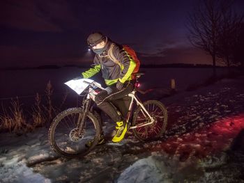 Sportsman sit on mountain bike during an night and shines into race itinerary. winter snow adventure