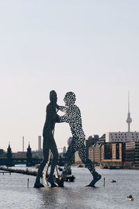 Statue in city against clear sky