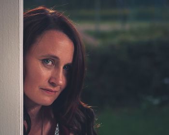 Close-up portrait of mature woman peeking from door