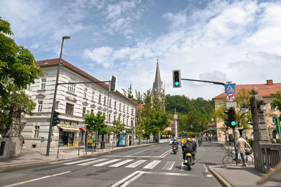 Road by buildings in city against sky