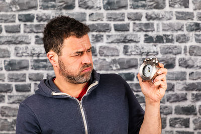 Midsection of man holding clock against wall