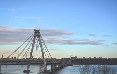 View of suspension bridge over river against cloudy sky