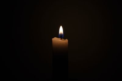 Close-up of burning candle against black background