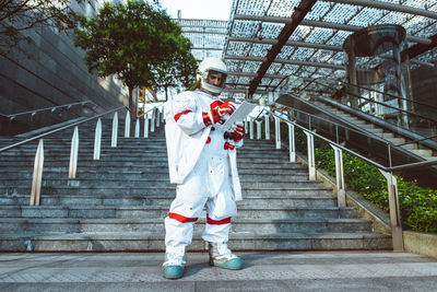 Full length of astronaut standing in front of staircase outdoors