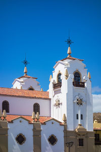 Low angle view of bell tower against clear blue sky