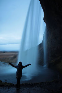 Woman standing on rock against waterfall in iceland