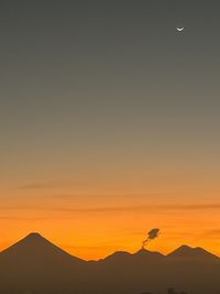 Silhouette woman standing against orange sky