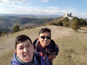 Portrait of smiling young couple on landscape against sky