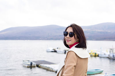 Portrait of young woman in sunglasses against mountains