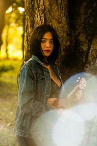 Portrait of young woman sitting on tree trunk