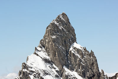 Low angle view of snowcapped mountain against clear blue sky