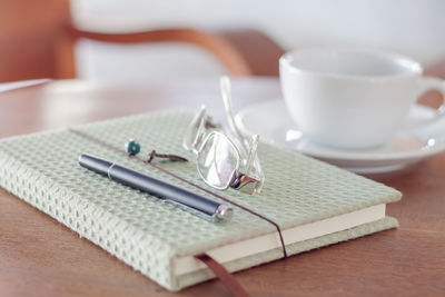 Pen with diary and cup on table