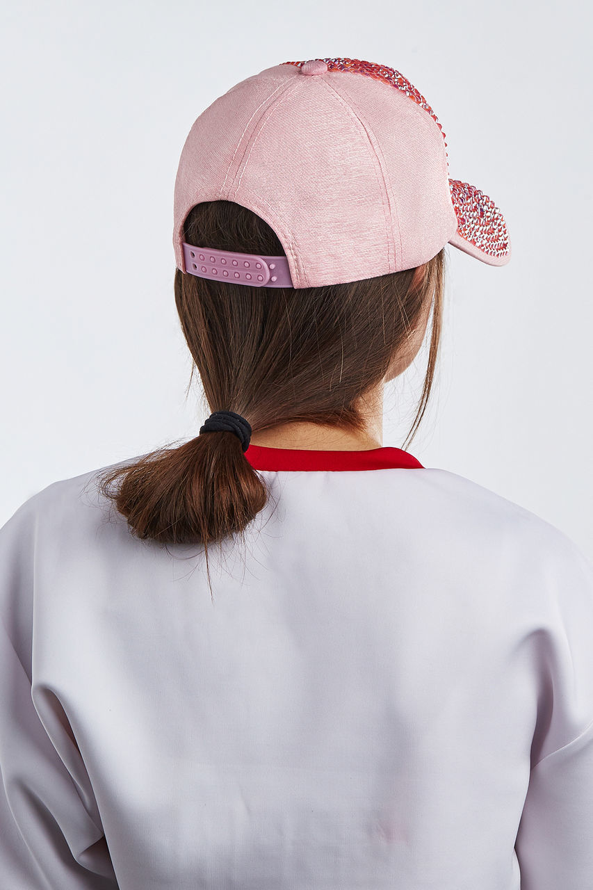 REAR VIEW OF WOMAN WEARING HAT AGAINST GRAY BACKGROUND