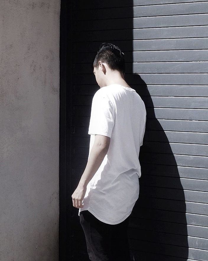 standing, three quarter length, looking away, wall - building feature, t-shirt, casual clothing, contemplation, young adult, well-dressed, thoughtful, profile