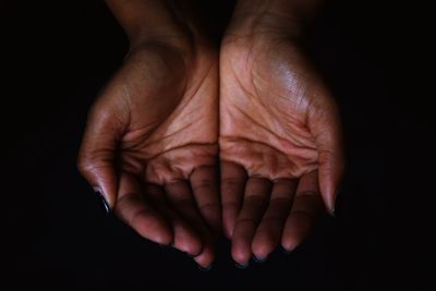 Cropped hands of woman against black background