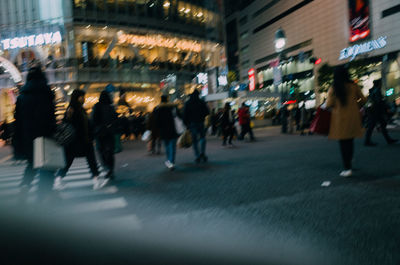 Blurred motion of people walking on road at night