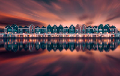 Scenic view of houses reflecting on sea against orange sky