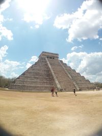 Tourists in front of historical building against cloudy sky