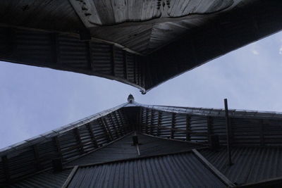 Low angle view of people on roof against sky