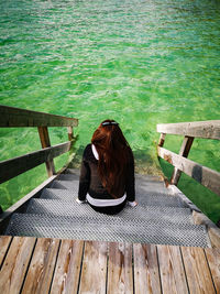 Rear view of woman sitting on wooden pier