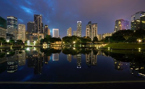 Reflection of illuminated cityscape against sky at night