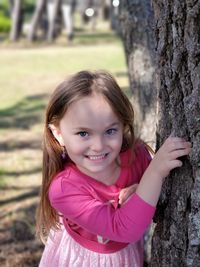 Portrait of cute girl smiling on tree trunk