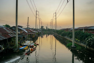 Sailboats on bridge over river against sky during sunset