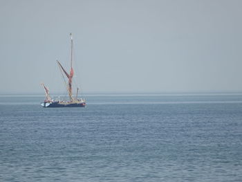 Sailboat sailing on sea against clear sky