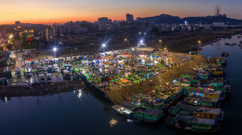 High angle view of illuminated city by river at night