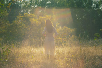 Rear view of woman standing on field