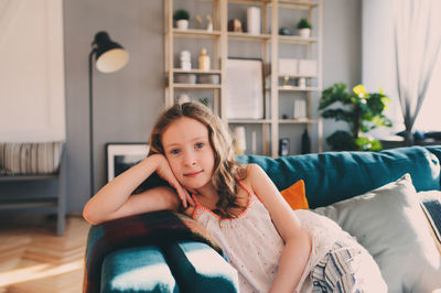 Portrait of beautiful young woman sitting on sofa at home