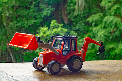 Red toy car on road by trees in forest