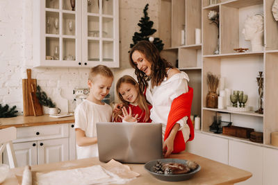 A happy family communicates online using a laptop at christmas in the kitchen at home in winter