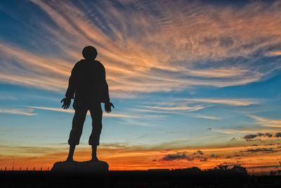 Silhouette man standing sculpture against sky during sunset