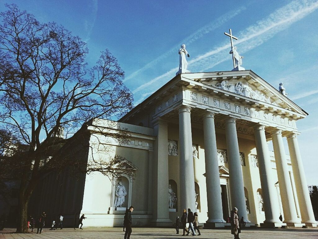 built structure, architecture, sky, tree, building exterior, low angle view, sunlight, blue, architectural column, bare tree, cloud, cloud - sky, day, outdoors, column, travel destinations, incidental people, shadow, railing