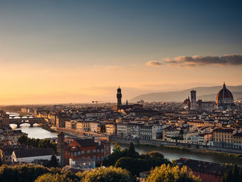 High angle view of river and buildings against sky during sunset