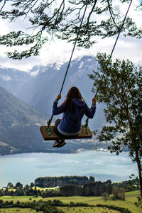 Full length of woman swinging on mountain against sky