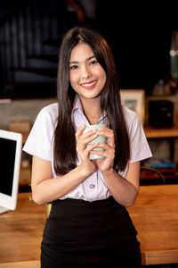 Portrait of smiling young woman using smart phone on table