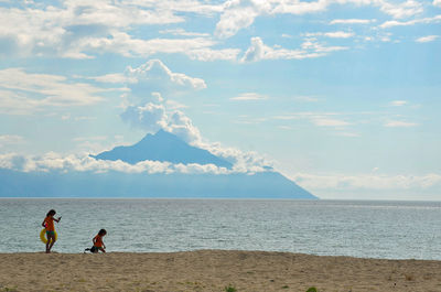 Girls playing at beach against mountain