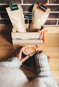 Midsection of woman holding coffee cup on table